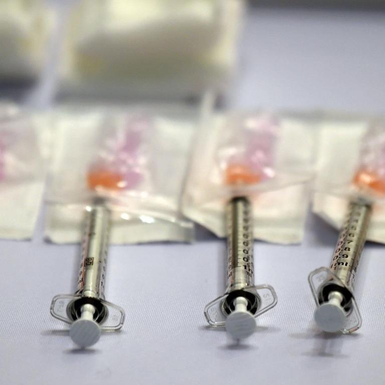 Fünf Spritzen liegen nebeneinander, die Nadeln in Dosen eines Corona-Impfstoffes, 2. April 2021, USA