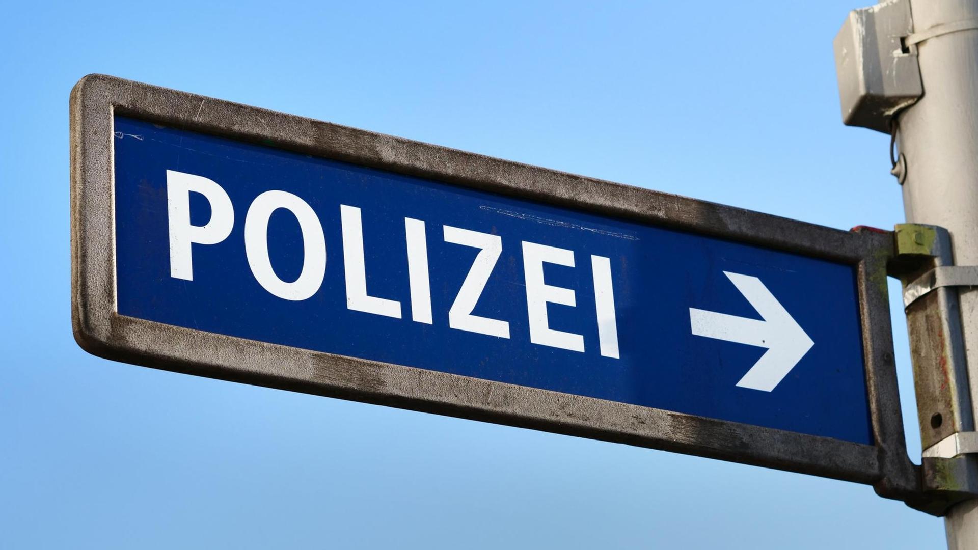 Ein Schild mit einem Pfeil weist den Weg zu einer nahegelegenen Polizeiwache in Berlin