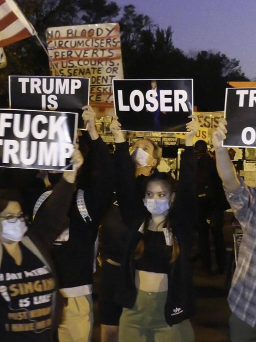 Eine Gruppe von Menschen demonstriert vor dem Weißen Haus gegen Donald Trump.
