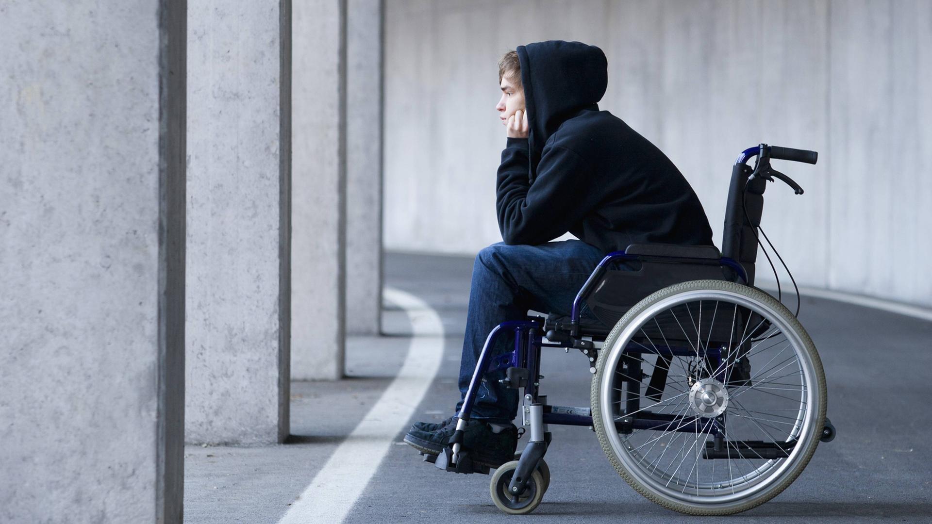 Ein junger Mann sitzt in einem Rollstuhl. Ein junger Mann sitzt in einem Rollstuhl.