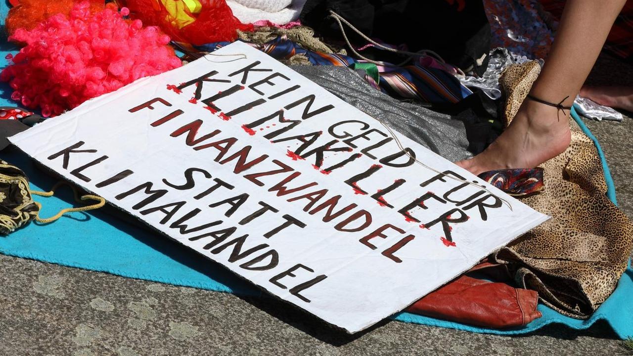 Ein Schild mit der der Aufschrift "Kein Geld für Klimakiller - Finanzwandel statt Klimawandel". Ein Schild mit der der Aufschrift "Kein Geld für Klimakiller - Finanzwandel statt Klimawandel".