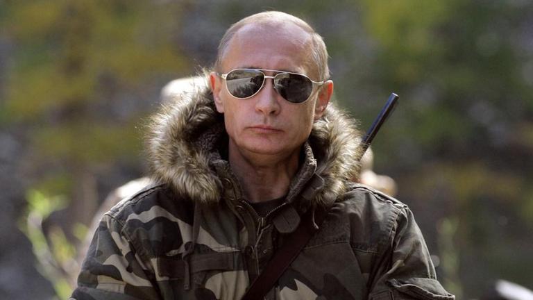 Wladimir Putin mit Gewehr über der Schulter auf einem Pferd sitzend. Wladimir Putin mit Gewehr über der Schulter auf einem Pferd sitzend.