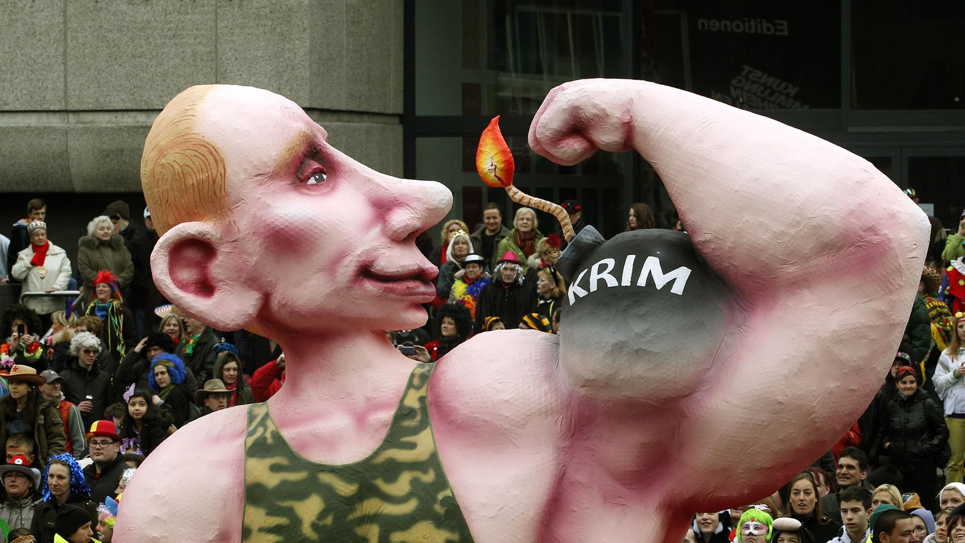 Ein Motivwagen auf dem Düsseldorfer Karnevalszug zeigt einen übergroßen Wladimir Putin in einem Camouflage-Unterhemd , der seinen Bizeps zeigt, auf dem "Krim" steht. Ein Motivwagen auf dem Düsseldorfer Karnevalszug zeigt einen übergroßen Wladimir Putin in einem Camouflage-Unterhemd , der seinen Bizeps zeigt, auf dem "Krim" steht.