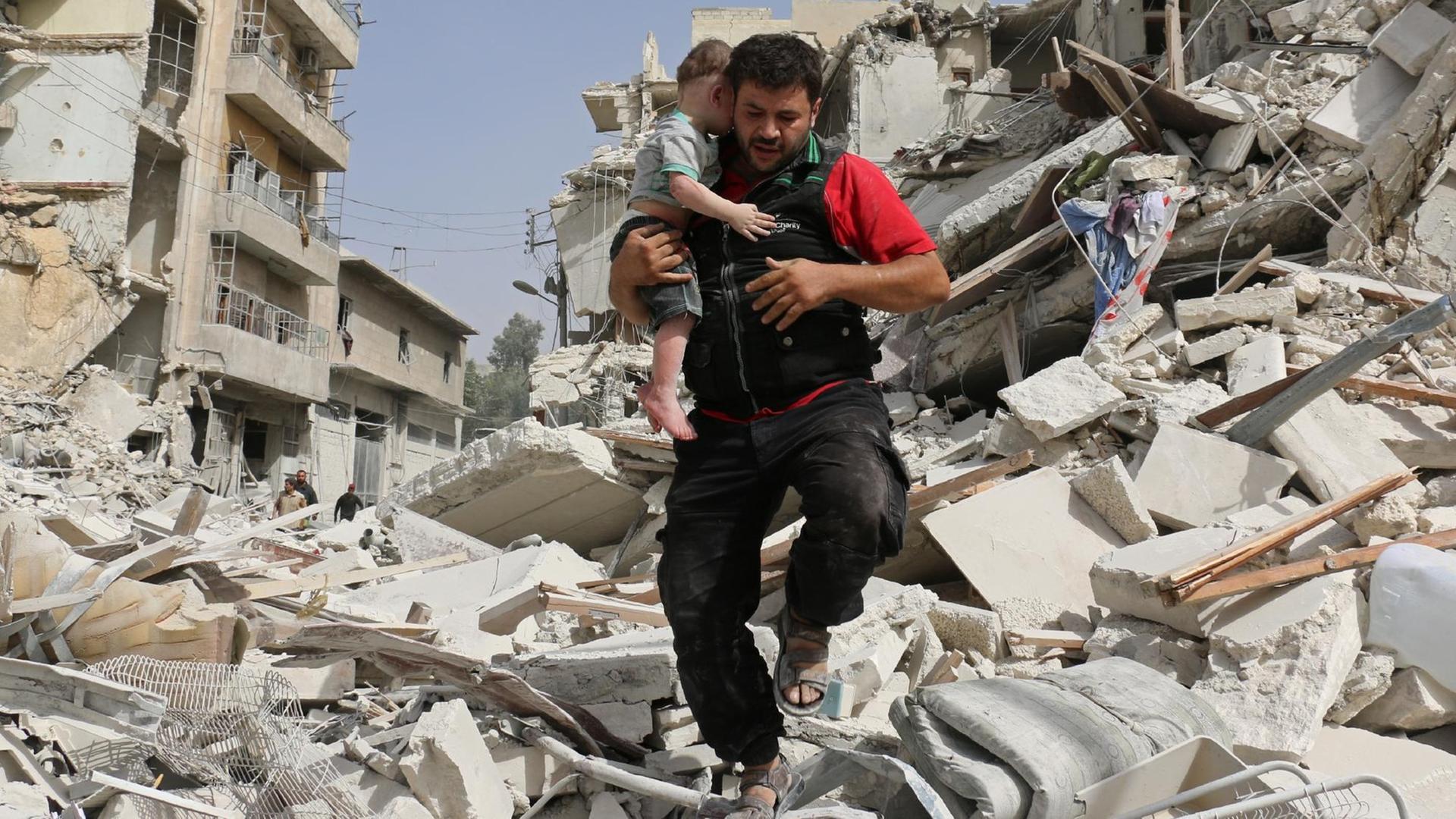 Ein Mann trägt sein Kind in Aleppo am Samstag, 24.09.2016, aus den Trümmern eines zerstörten Gebäudes. Ein Mann trägt sein Kind in Aleppo am Samstag, 24.09.2016, aus den Trümmern eines zerstörten Gebäudes.