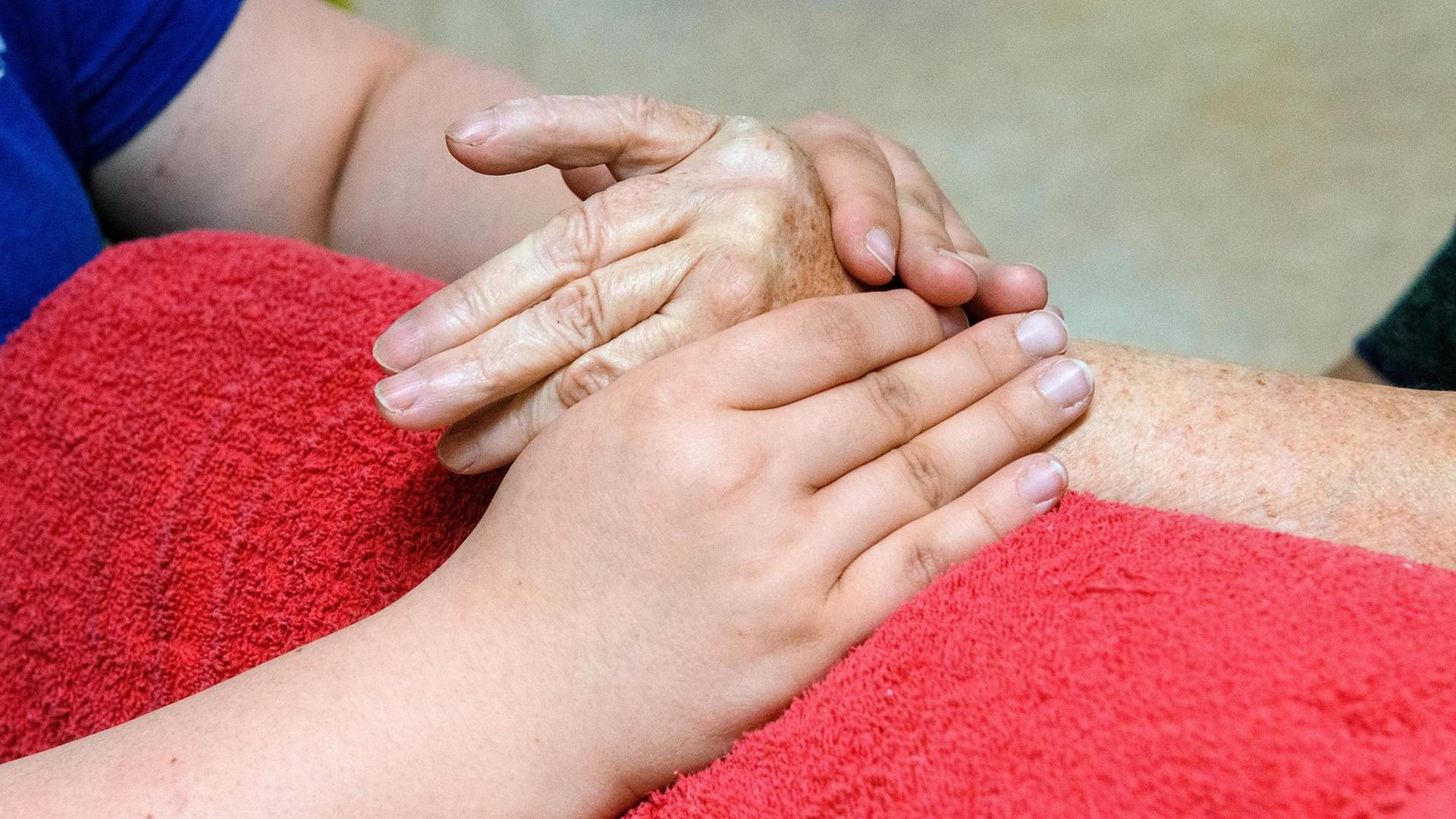 Hände einer an Arthritis erkrankten Patientin werden von einer Ergotherapeutin massiert. Die Massage der Hände wärmt und mobilisiert die entzuendeten Gelenke der Hand. Hände einer an Arthritis erkrankten Patientin werden von einer Ergotherapeutin massiert. Die Massage der Hände wärmt und mobilisiert die entzuendeten Gelenke der Hand.