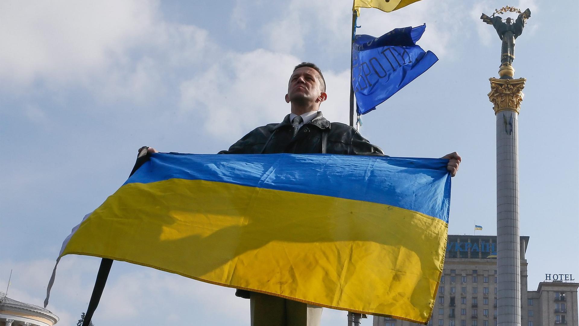 Ein Ukrainer hält in Kiew die Nationalflagge in die Höhe. Ein Ukrainer hält in Kiew die Nationalflagge in die Höhe.