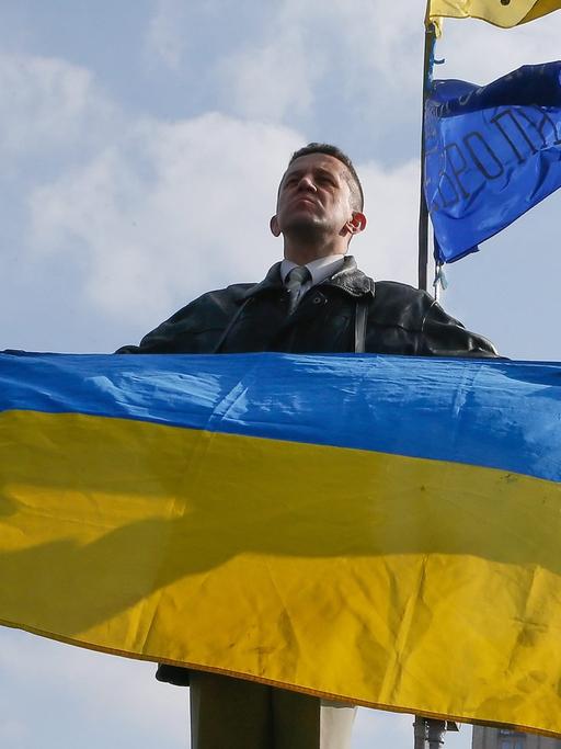 Ein Ukrainer hält in Kiew die Nationalflagge in die Höhe.