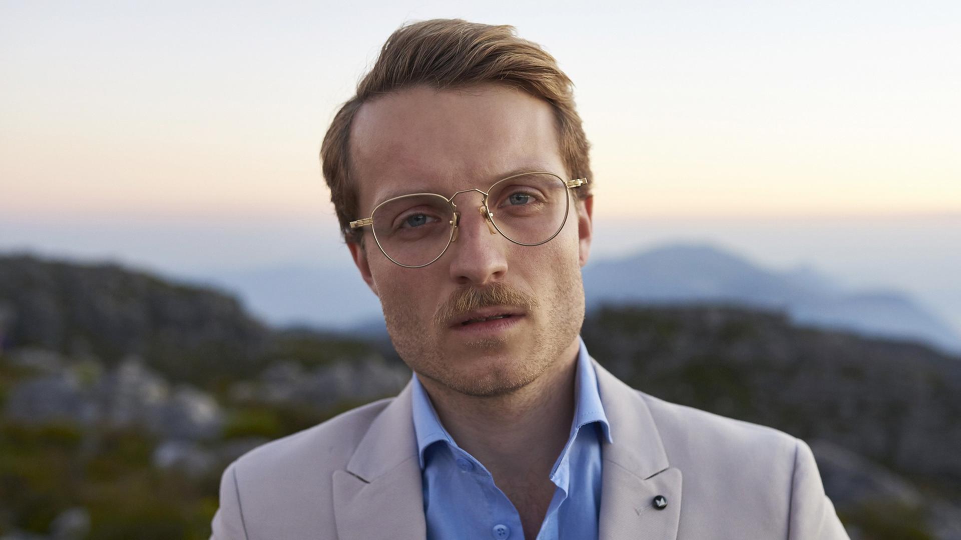Künstler Andy Kassier, Vollportrait vor Sonnenuntergang, Die Goldrandbrille glänzt Künstler Andy Kassier, Vollportrait vor Sonnenuntergang, Die Goldrandbrille glänzt