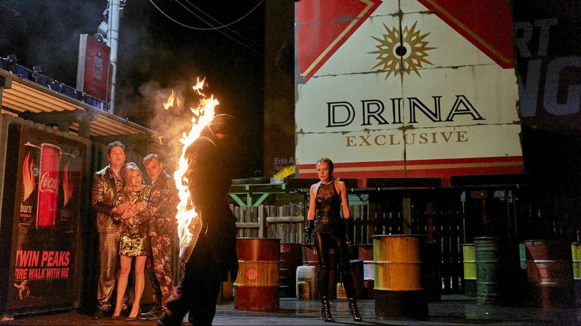 Ein Mann in Flammen auf der Bühne – umgeben von vier Schauspielerinnen und Schauspielern. Ein Mann in Flammen auf der Bühne – umgeben von vier Schauspielerinnen und Schauspielern.
