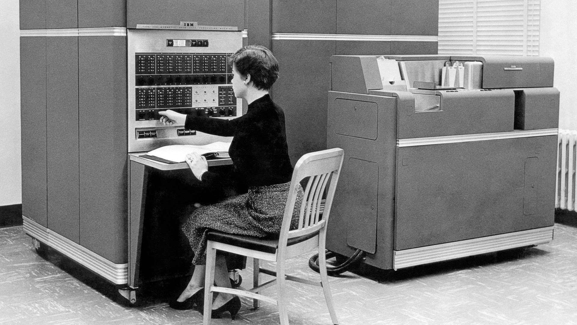 Schwarzweißaufnahme einer Frau, die 1954 in New York vor dem Computer IBM 650 sitzt.