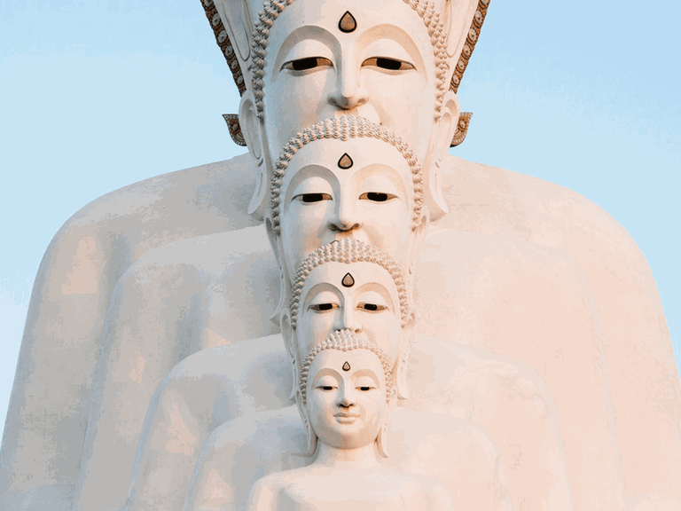 Mehrere weiße Buddha-Statuen stehen hintereinander.