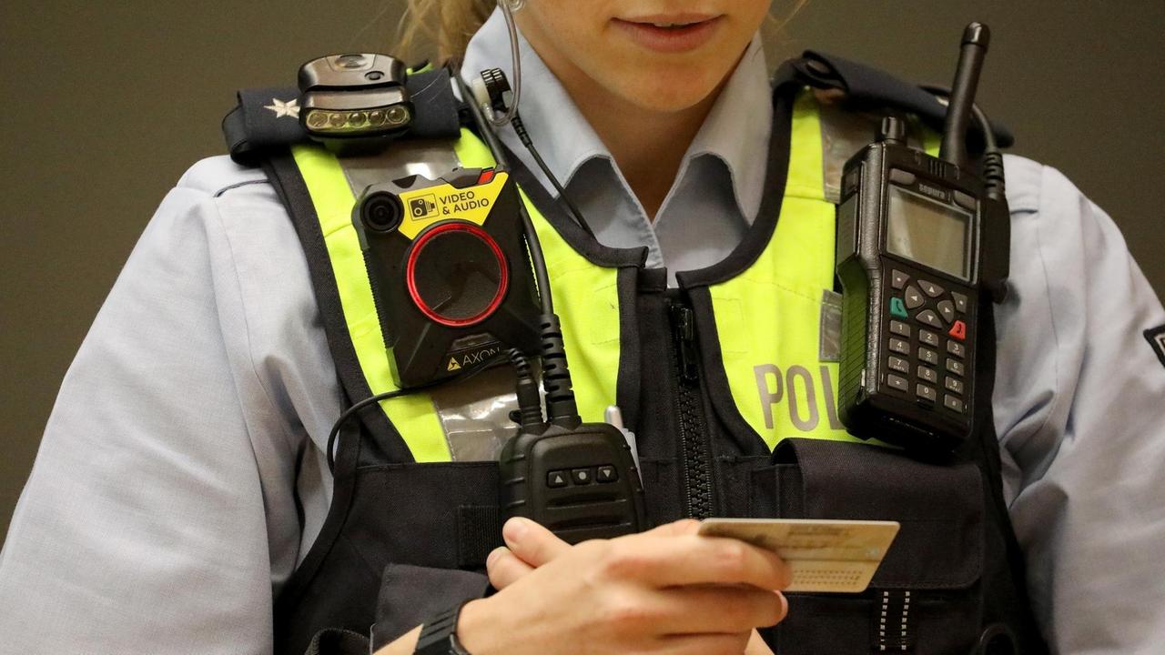 Eine Polizistin in Köln überprüft mit einer laufenden Bodycam bei einer Vorführung einen Ausweis