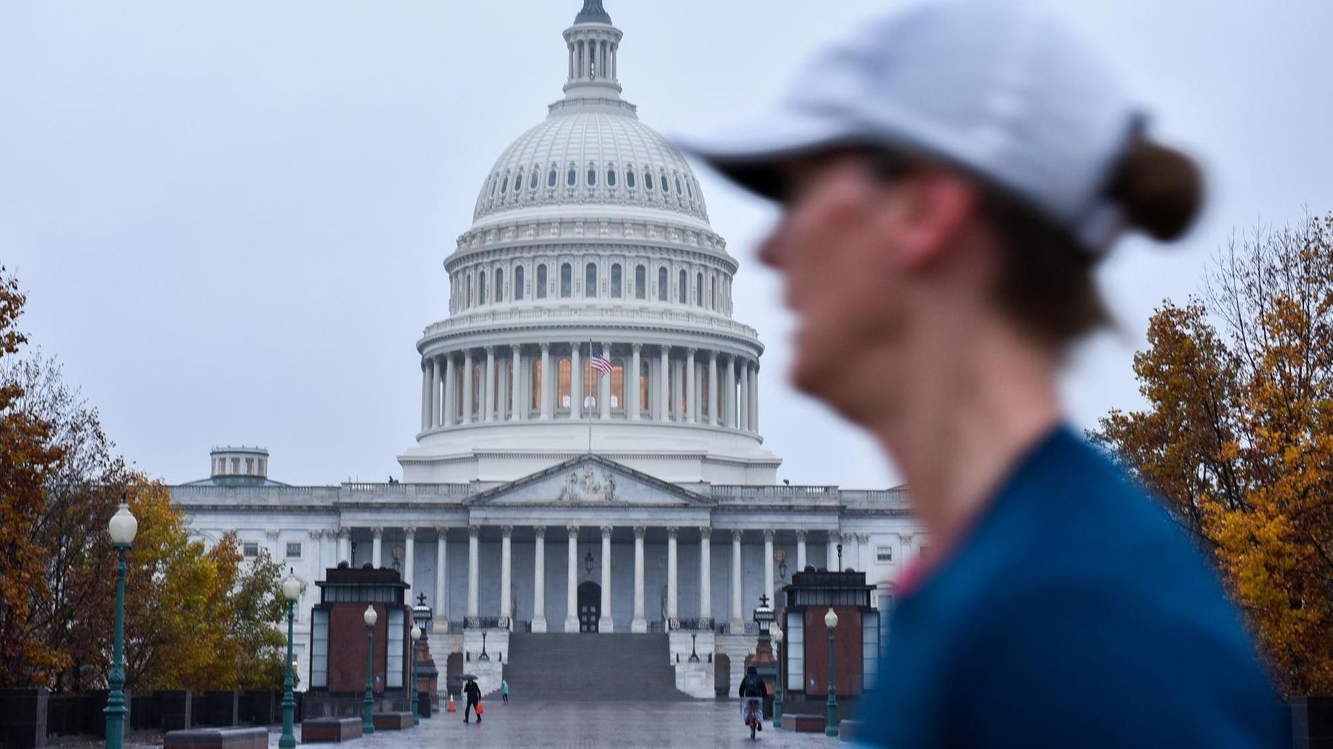 Eine Frau mit Baseball-Kappe läuft am Kapitol in Washington vorbei. Eine Frau mit Baseball-Kappe läuft am Kapitol in Washington vorbei.