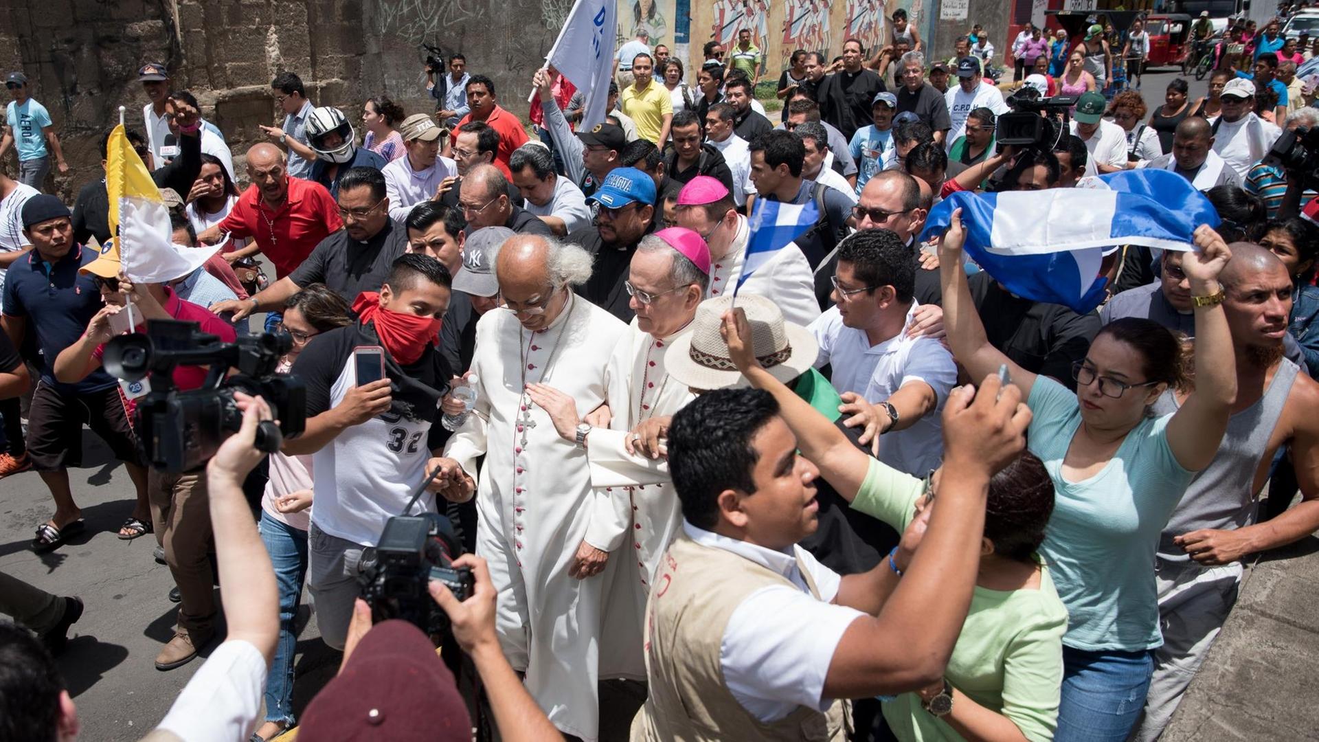 Der Erzbischof von Managua, Kardinal Leopoldo Brenes (M) und der Nuntius in Nicaragua, Erzbischof Waldemar Stanislaw Sommertag (M), versuchen in eine Kirche zu gelangen, in der mindestens neuen Menschen Zuflucht gesucht haben.