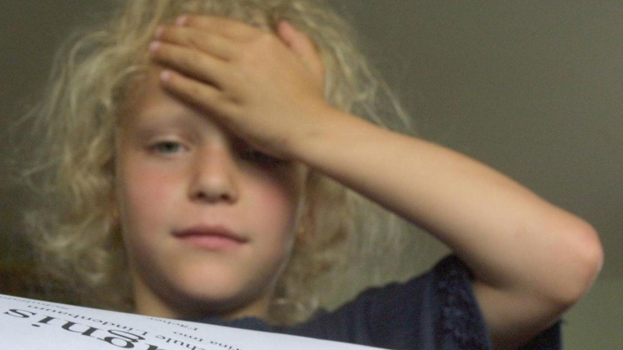 Ein Mädchen begutachtet ihr Zeugnis und hält sich die Hand an die Stirn. Ein Mädchen begutachtet ihr Zeugnis und hält sich die Hand an die Stirn.
