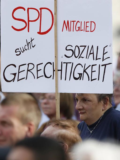 Bei einer Veranstaltung hält ein Zuschauer ein Transparent hoch: "SPD-Mitglied sucht soziale Gerechtigkeit"
