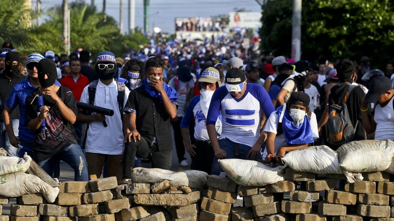 Nicaragua, Managua: Demonstranten gehen während eines Protests gegen Präsident Ortega hinter einer Barrikade in Deckung.