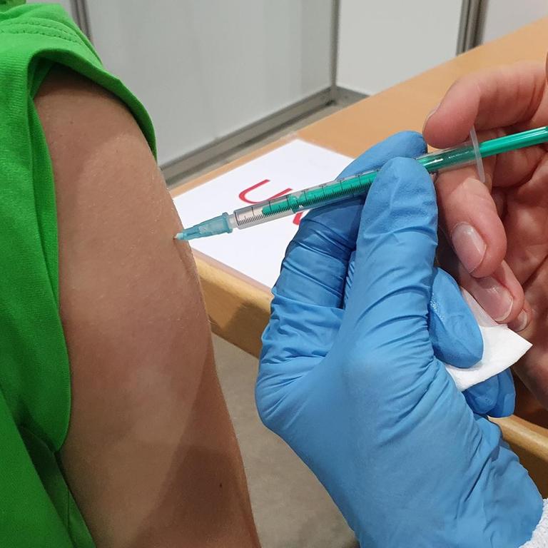 Ein Patient/eine Patientin bekommt eine Impfung gegen das Coronavirus. Die Hand eines Arztes/einer Ärztin hält die Spritze.