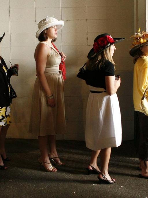 Weibliche Rennbahnbesucher warten vor der Toilette.