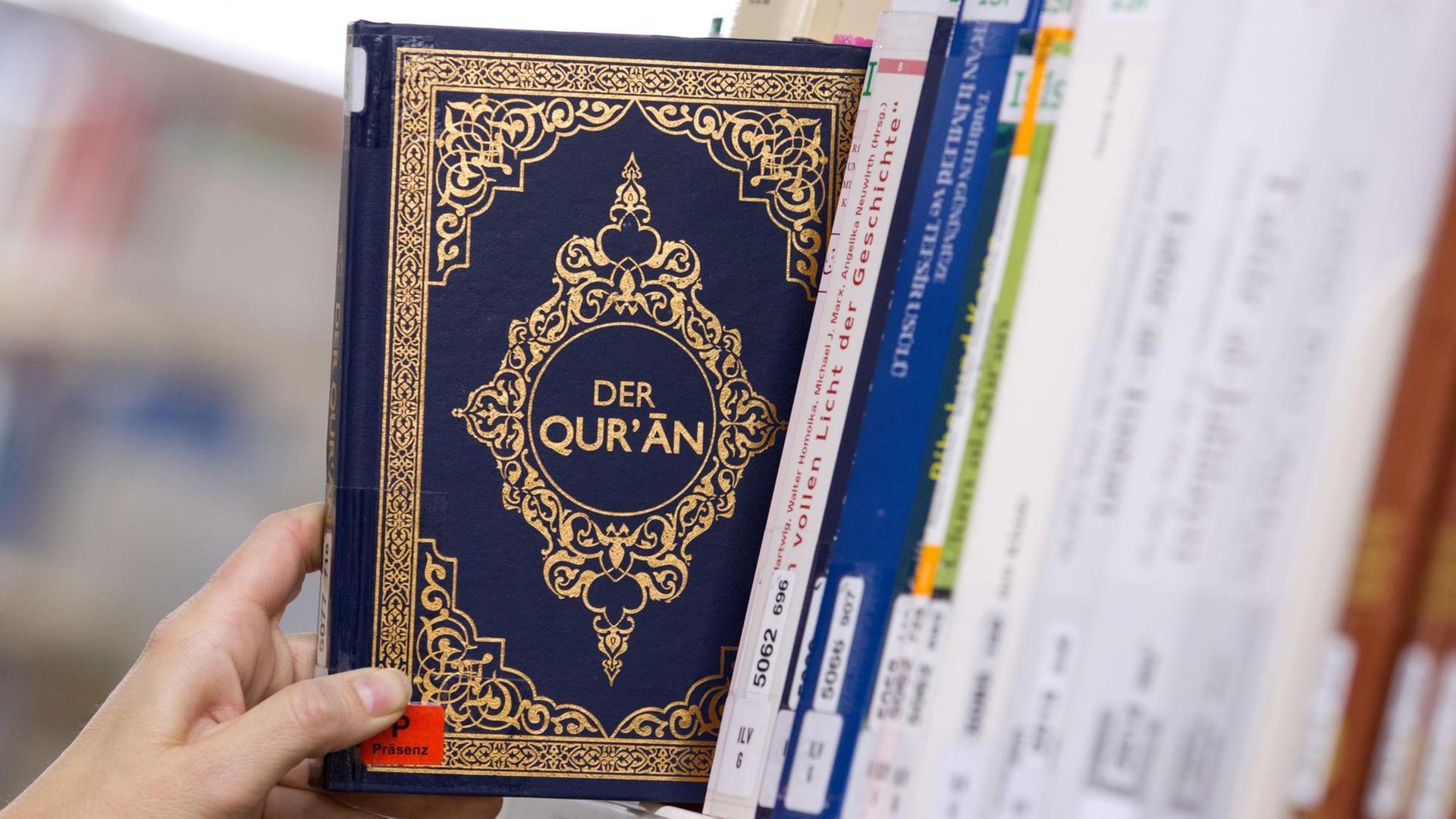 Eine Ausgabe des Koran (Quran) wirdaus einem Regal gezogen