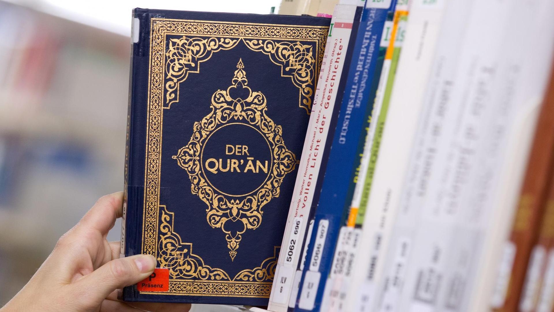 Eine Ausgabe des Koran (Quran) wirdaus einem Regal gezogen Eine Ausgabe des Koran (Quran) wirdaus einem Regal gezogen