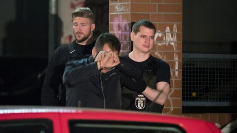 Polizisten führen bei einem Einsatz eine Person in Handschellen aus einem Haus in Berlin im Bezirk Neukölln.
