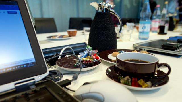 Süßigkeiten, Kaffee und Kekse stehen am 17.01.2015 während eines Meetings in einem Büro in Berlin neben einem Laptop. Foto: Arno Burgi | Verwendung weltweit
