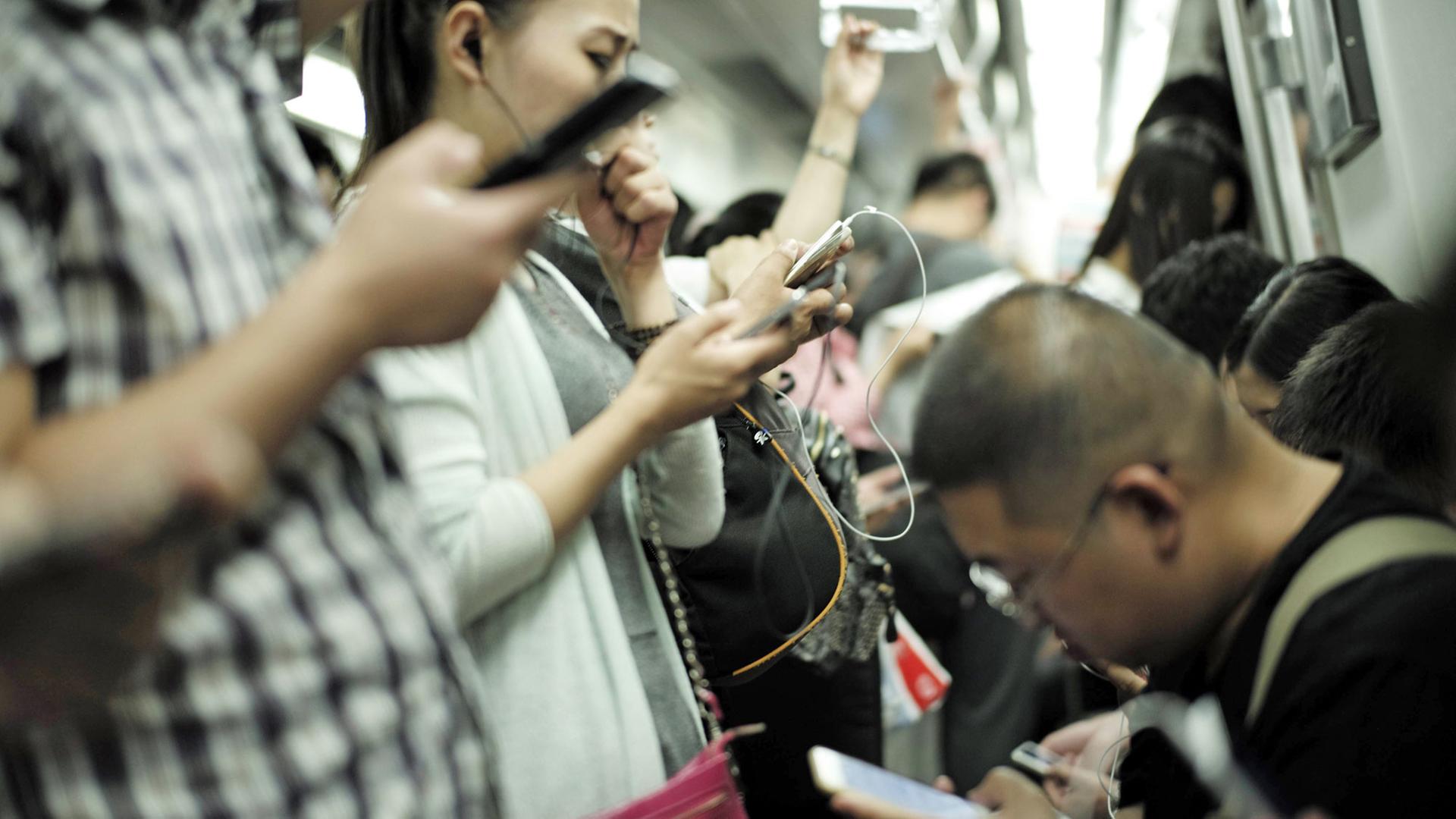Fahrgäste in der U-Bahn der chinesischen Hauptstadt Peking benutzen ihre Smartphones.