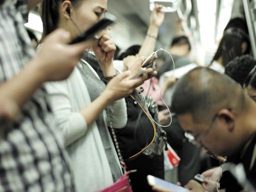 Fahrgäste in der U-Bahn der chinesischen Hauptstadt Peking benutzen am 3.7.2015 ihre Smartphones.