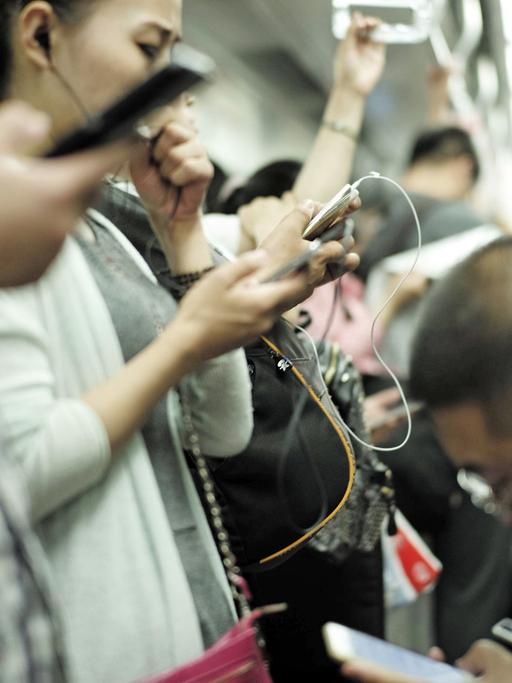 Fahrgäste in der U-Bahn der chinesischen Hauptstadt Peking benutzen am 3.7.2015 ihre Smartphones.