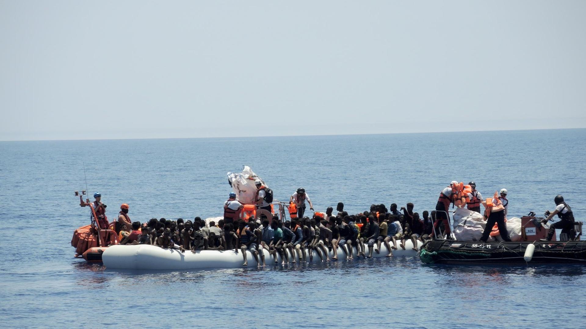 Rettungskräfte der Hilfsorganisationen Ärzte ohne Grenzen und SOS Méditerranée nähern sich einem überfüllten Schlauchboot im Mittelmeer. Die Menschen wurden auf das Rettungsschiff "Aquarius" gebracht. Rettungskräfte der Hilfsorganisationen Ärzte ohne Grenzen und SOS Méditerranée nähern sich einem überfüllten Schlauchboot im Mittelmeer. Die Menschen wurden auf das Rettungsschiff "Aquarius" gebracht.