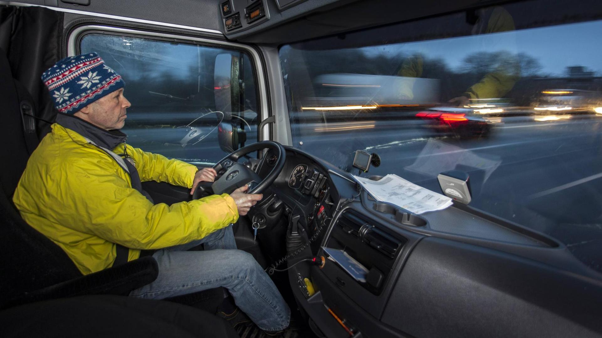 Ein LKW-Fahrer sitzt hinter dem Steuer seines Fahrzeugs. Ein LKW-Fahrer sitzt hinter dem Steuer seines Fahrzeugs.