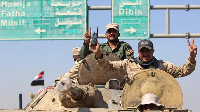 Irakische Soldaten sitzen auf einem Panzer, im Hintergrund Verkehrsschilder