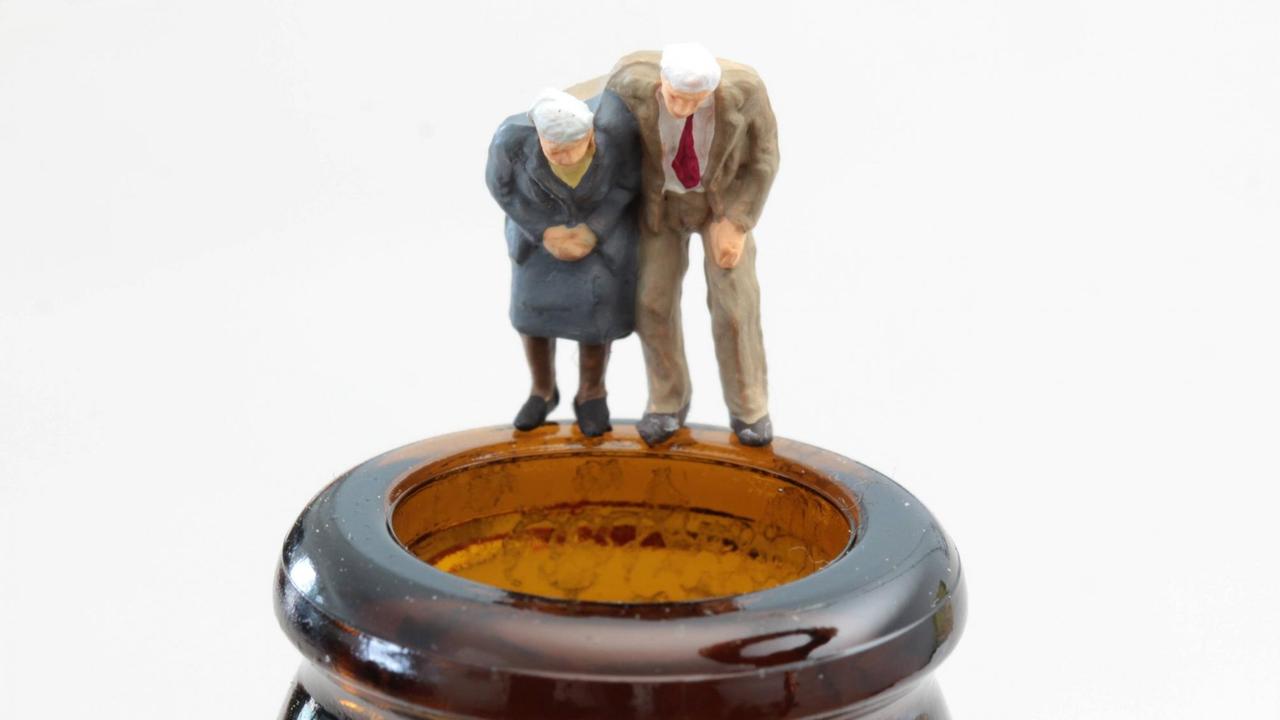 Figuren als altes Seniorenpaar steht auf dem dem Rand einer Bierflasche. Figuren als altes Seniorenpaar steht auf dem dem Rand einer Bierflasche.