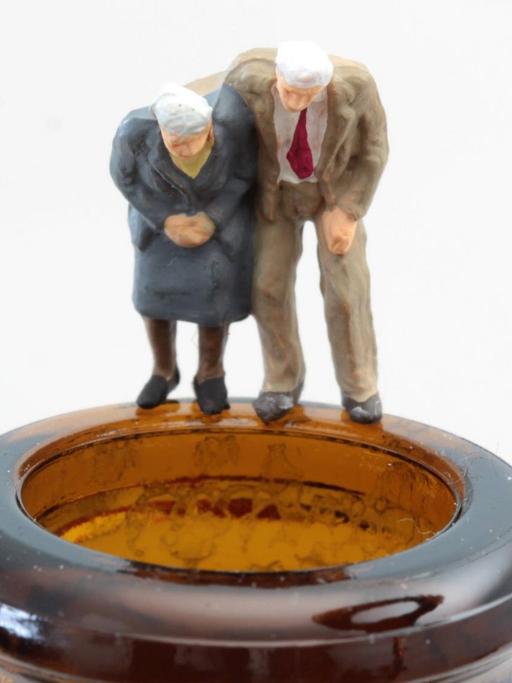 Figuren als altes Seniorenpaar steht auf dem dem Rand einer Bierflasche.