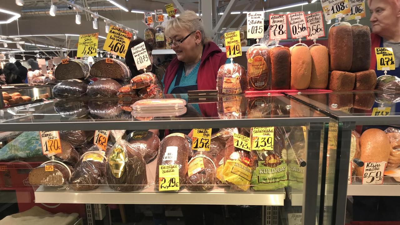 Eine Frau steht auf dem Wochenmarkt in Riga und verkauft Fleisch- und Wurstwaren. 