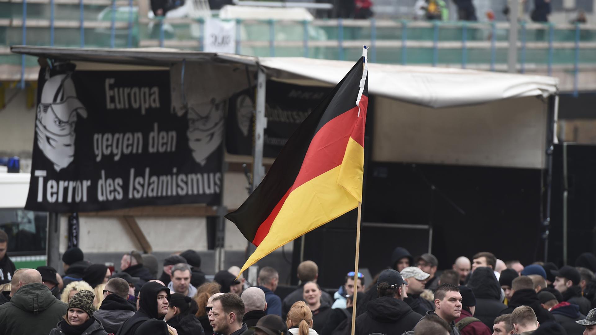 GERMANY, HANOVER : A participant holds up a German flag as far-right hooligans rally against Islamist extremism under the banner 'Hooligans against Salafism' (HoGeSa) at the former central bus station near the main train station, on November 15, 2014 in Hanover, central Germany. Around 5000 hooligans are expected to take part in the rally. AFP PHOTO / ODD ANDERSEN GERMANY, HANOVER : A participant holds up a German flag as far-right hooligans rally against Islamist extremism under the banner 'Hooligans against Salafism' (HoGeSa) at the former central bus station near the main train station, on November 15, 2014 in Hanover, central Germany. Around 5000 hooligans are expected to take part in the rally. AFP PHOTO / ODD ANDERSEN