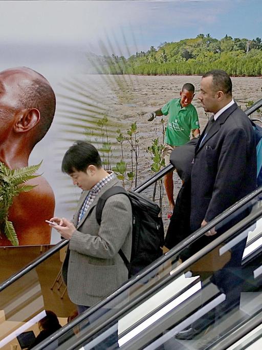 Delegierte gehen am 06.11.2017 in Bonn (Nordrhein-Westfalen) auf der Weltklimakonferenz an einem Plakat der Fidschi-Inseln vorbei. Die Weltklimakonferenz COP23 findet 06. bis 17. November 2017 in Bonn statt.