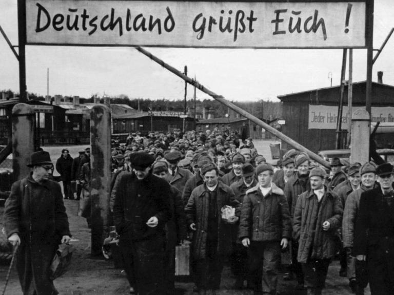 "Deutschland grüßt Euch" steht auf einem Schild über dem geöffneten Schlagbaum des Entlassungslagers Gronenfelde bei Frankfurt an der Oder. Die aus russischer Kriegsgefangenschaft entlassenen Heimkehrer treten von hier aus die Reise in ihre Heimatorte an. Aufgenommen am 12. April 1949.