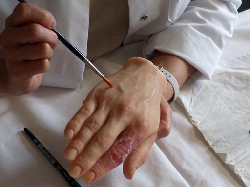 Navena Widulin, medizinische Präparatorin an der Berliner Charité, bemalt die Wachsmoulage einer Hand.