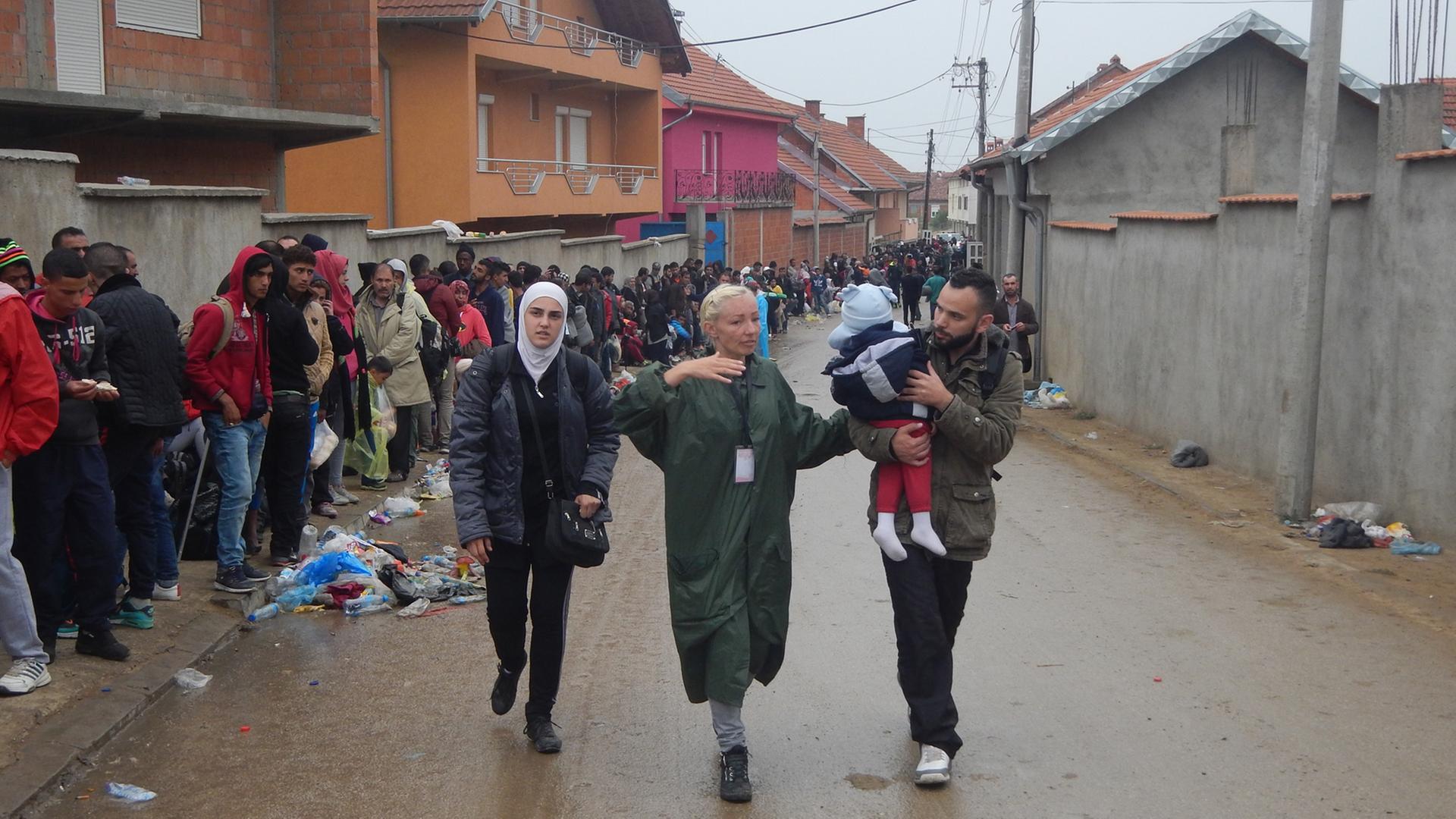 Helferin Dafina zeigt einer Flüchtlingsfamilie den Weg.