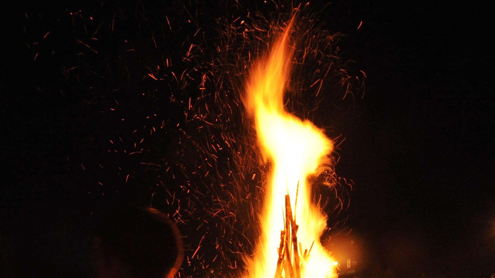 Menschen stehen nachts um ein Lagerfeuer herum. Menschen stehen nachts um ein Lagerfeuer herum.