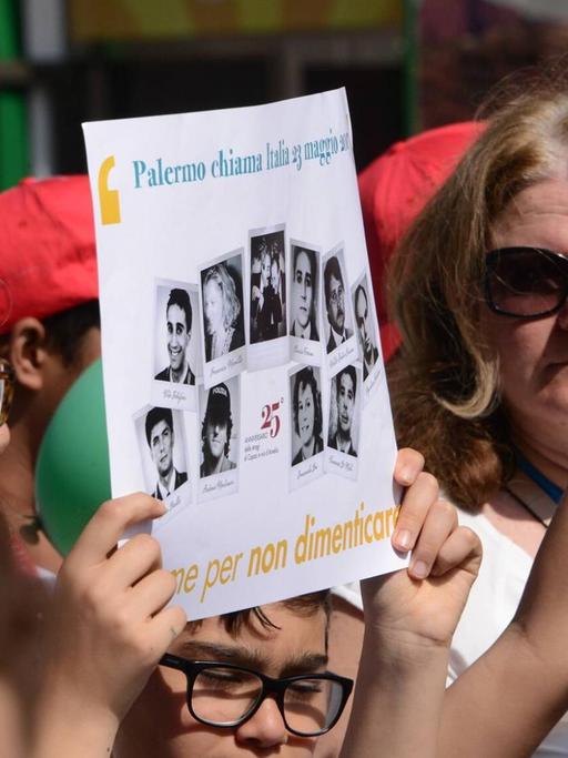 Demonstrationen im Mai 2017 in Palermo, im Gedenken an den Bombenanschlag auf die Richter Giovanni Falcone und Paolo Borsellino vor 25 Jahren. Vorne im Bild halten Demonstranten ein Plakat mit Fotos und eine italienische Flagge.