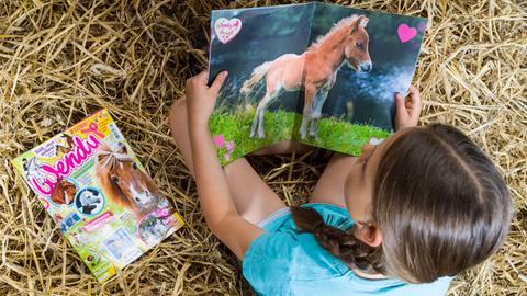 Ein Mädchen liest die Pferdezeitschrift für Kinder "Wendy" im Jahr2016 auf einem Reiterhof