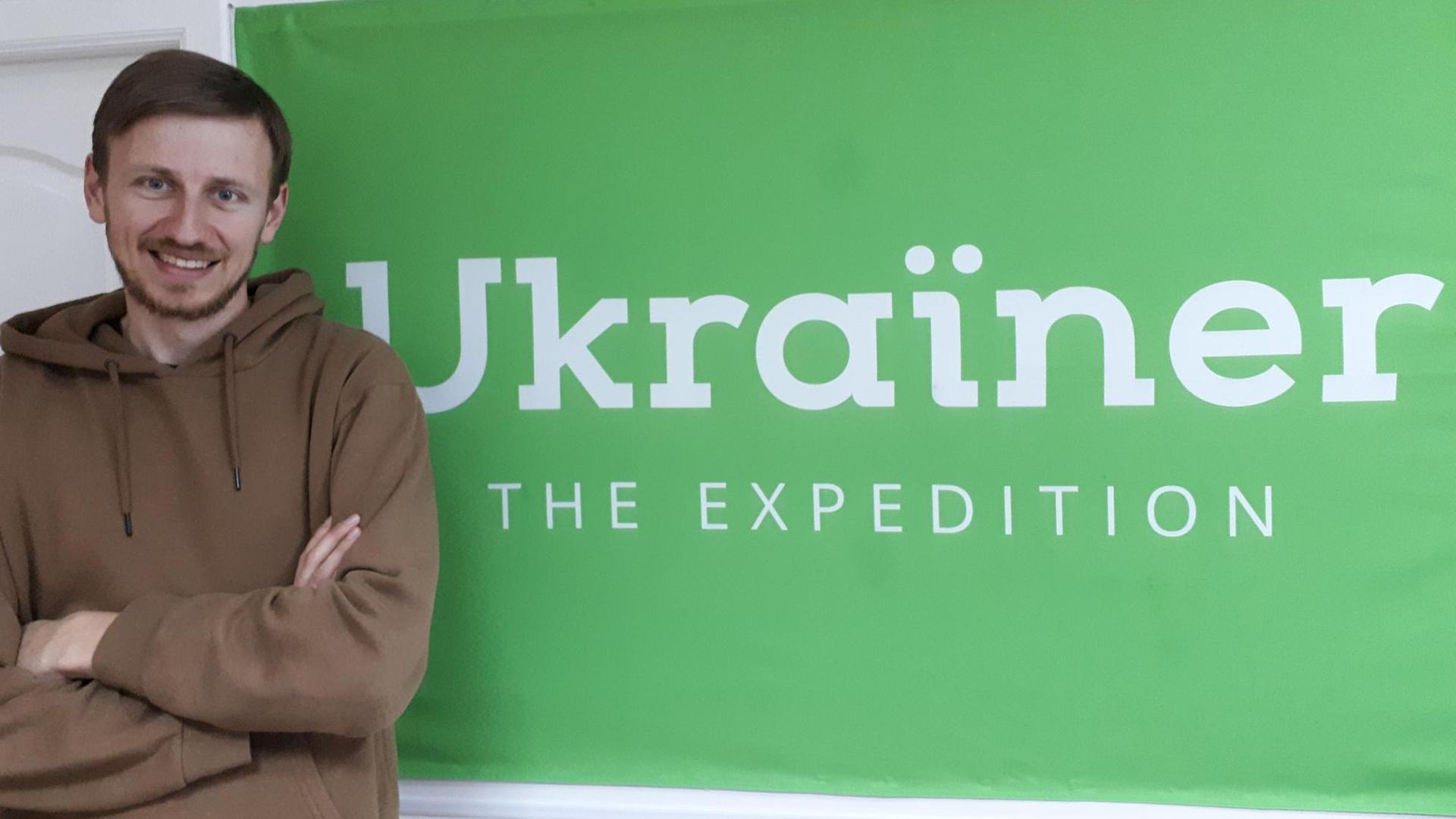 Bogdan Logvynenko, Mitgründer des multimedialen Magazins "Ukrainer" steht vor einem Plakat "Ukrainer"