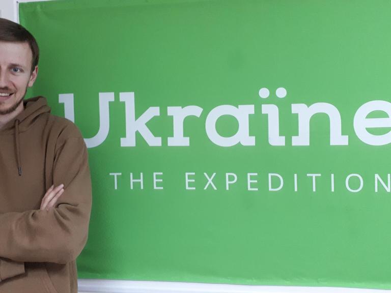 Bogdan Logvynenko, Mitgründer des multimedialen Magazins "Ukrainer" steht vor einem Plakat "Ukrainer"