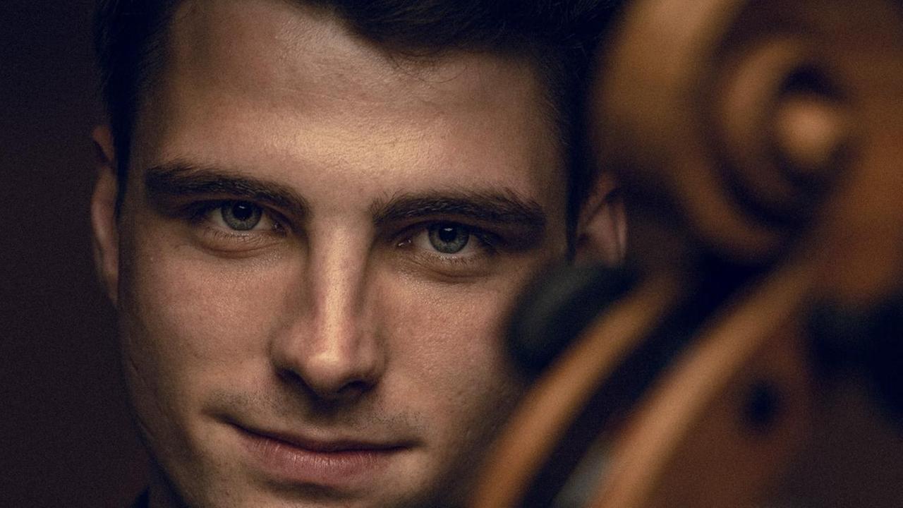 Der Cellist blickt direkt in die Kamera, vor der auch unscharft die Schnecke des Cellos zu sehen ist. Der Cellist blickt direkt in die Kamera, vor der auch unscharft die Schnecke des Cellos zu sehen ist.