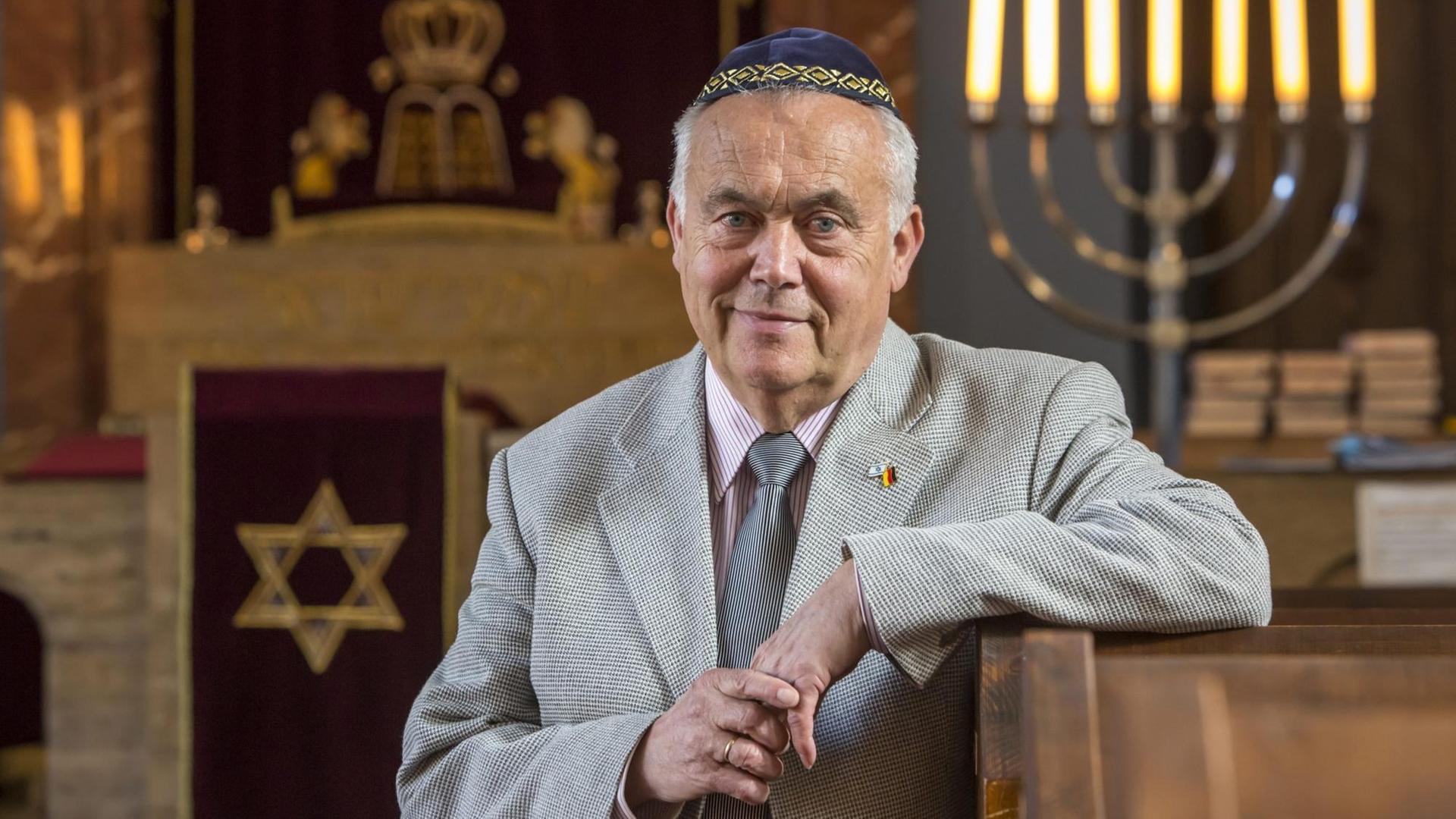 Reinhard Schramm, Vorsitzender der Jüdischen Landesgemeinde Thüringen, in einer Synagoge, in die Kamera lächelnd, den Arm auf eine Bank gestützt Reinhard Schramm, Vorsitzender der Jüdischen Landesgemeinde Thüringen, in einer Synagoge, in die Kamera lächelnd, den Arm auf eine Bank gestützt