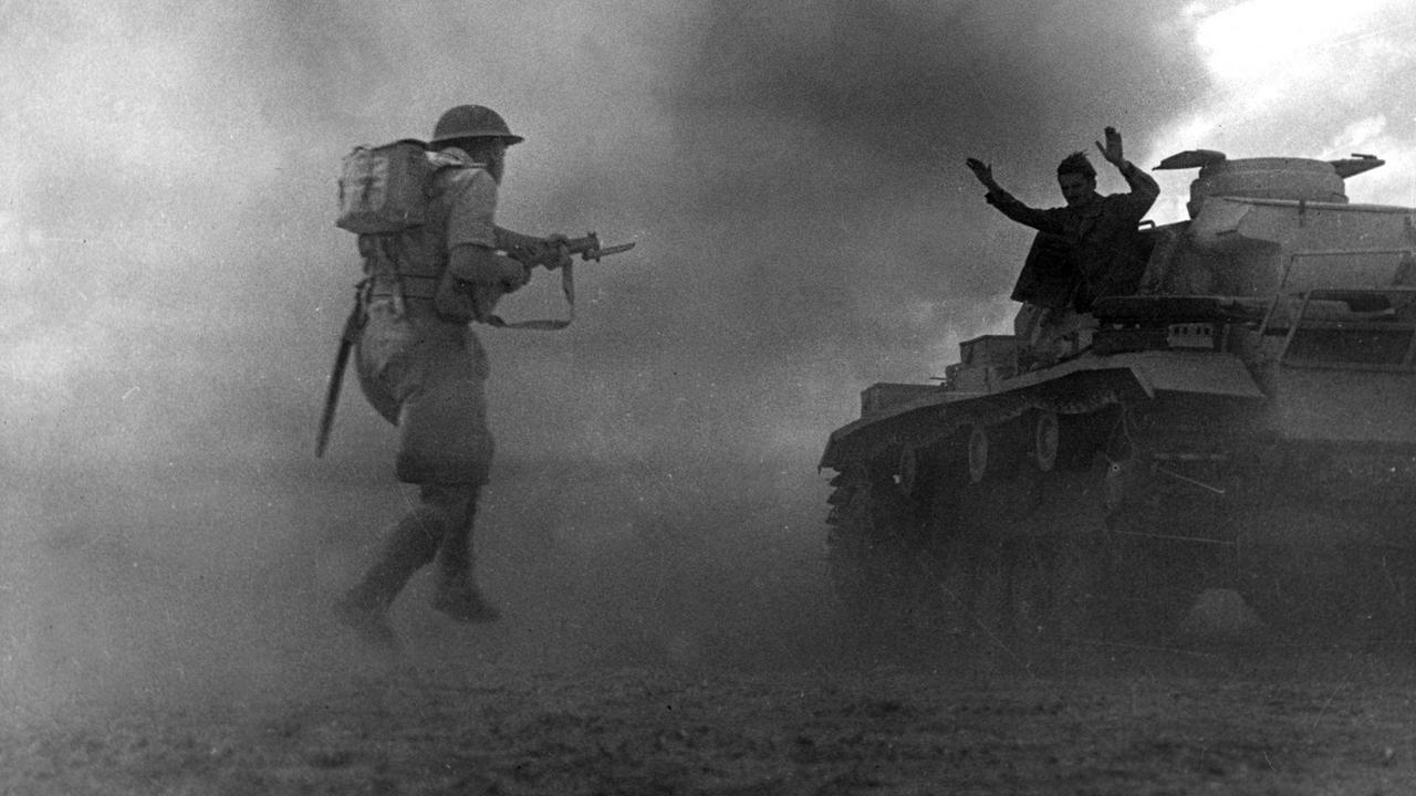 Schwarzweißaufnahme in dramatischer Perspektive: Ein britischer Soldat stürmt einen Panzer, auf dem sich ein nur als Silhouette erkennbarer Soldat mit erhobenen Händen ergibt