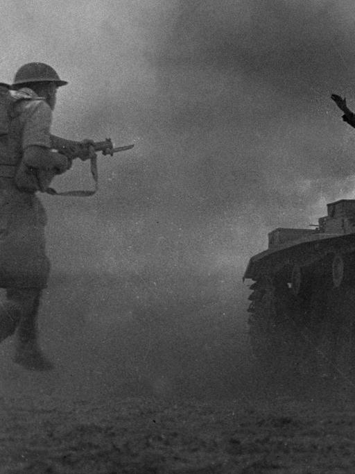 Schwarzweißaufnahme in dramatischer Perspektive: Ein britischer Soldat stürmt einen Panzer, auf dem sich ein nur als Silhouette erkennbarer Soldat mit erhobenen Händen ergibt